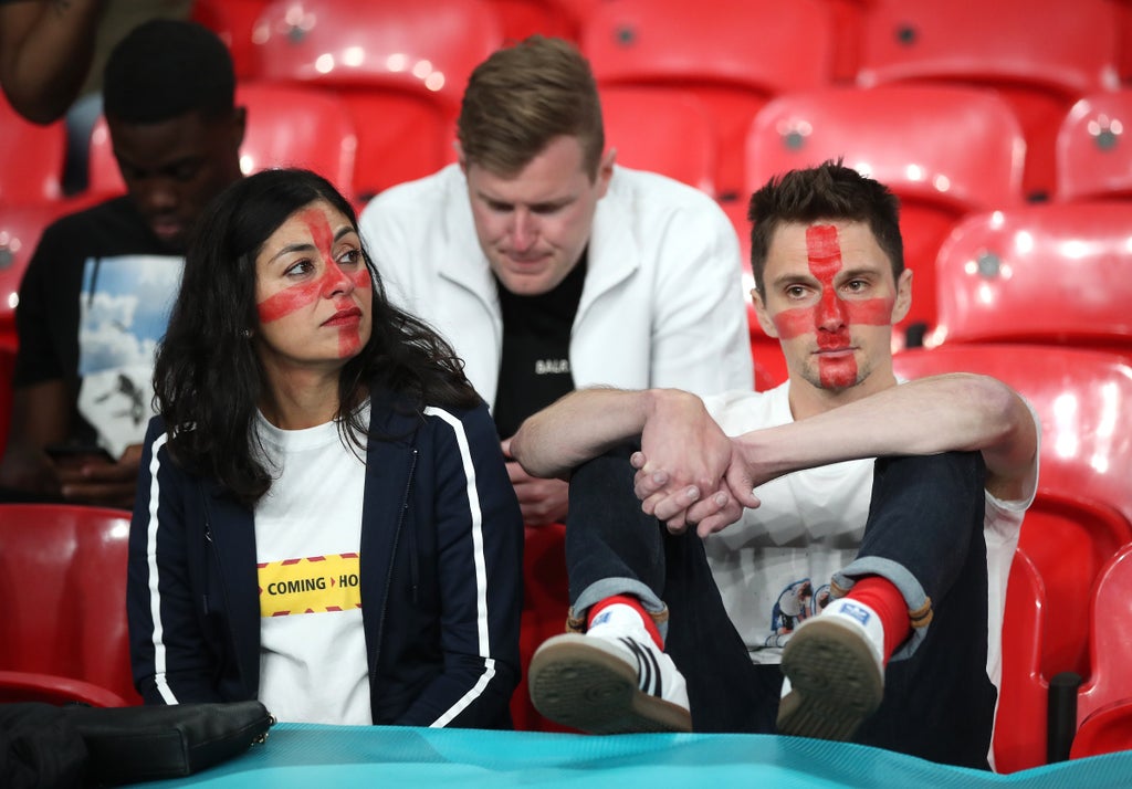 一群人坐在椅子上：2020 年欧洲杯决赛后点球大战失利，英格兰球迷沮丧地坐在看台上（尼克·波茨/宾夕法尼亚州）